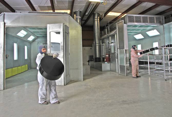 A shop with regulation paint booths and workers in paint safety gear.